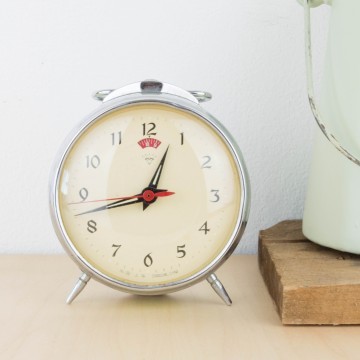 Antiguo reloj despertador de metal en verde pastel