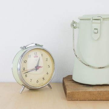 Antiguo reloj despertador de metal en verde pastel